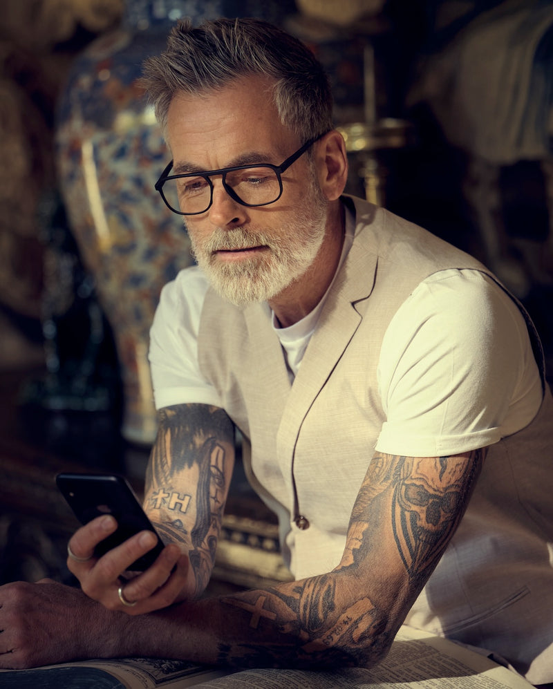 Man with glasses looks at his smartphone